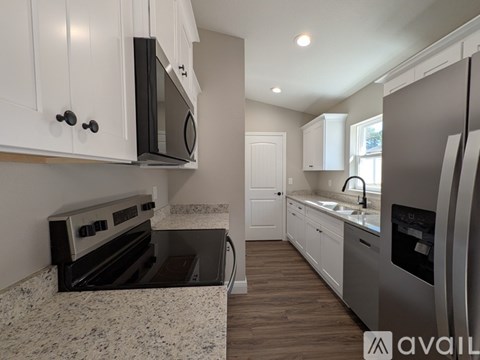 A kitchen with white cabinets and a granite countertop.