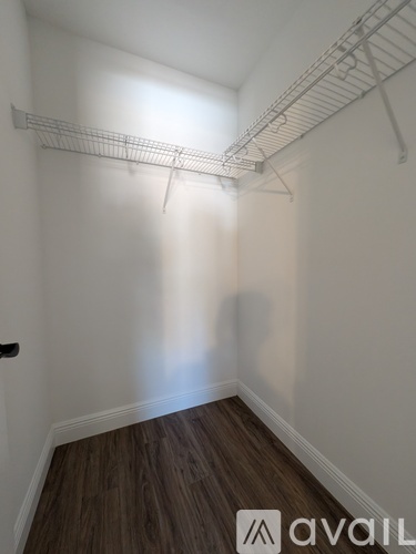 A room with a white wall and a wooden floor with a metal rack on the wall.