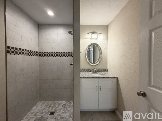 A bathroom with a tiled shower and a vanity with a mirror.