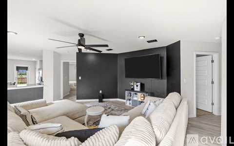 A living room with a large couch and a flat screen TV mounted on the wall.