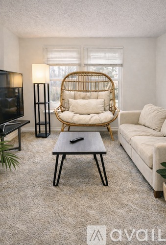 A living room with a white couch, a black coffee table, and a rattan chair.