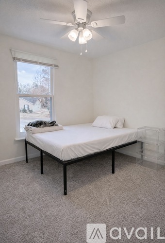 A bedroom with a bed, pillows, and a ceiling fan.