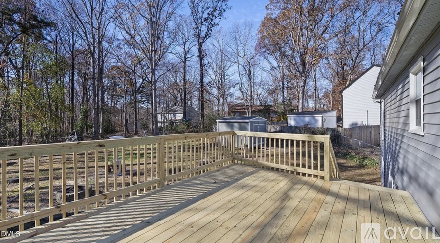A wooden deck with a railing and trees in the background.