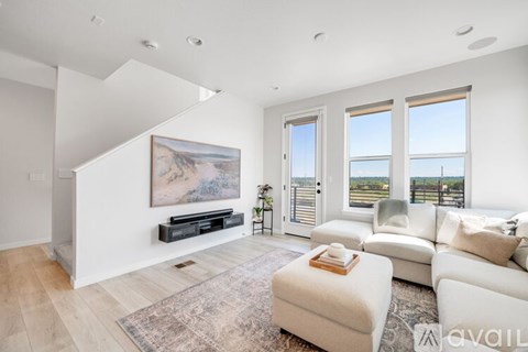 A living room with a large painting on the wall and a view of the outside through the windows.