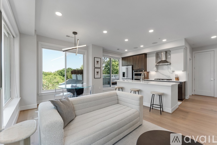 A modern living room with a white couch and a kitchen area in the background.