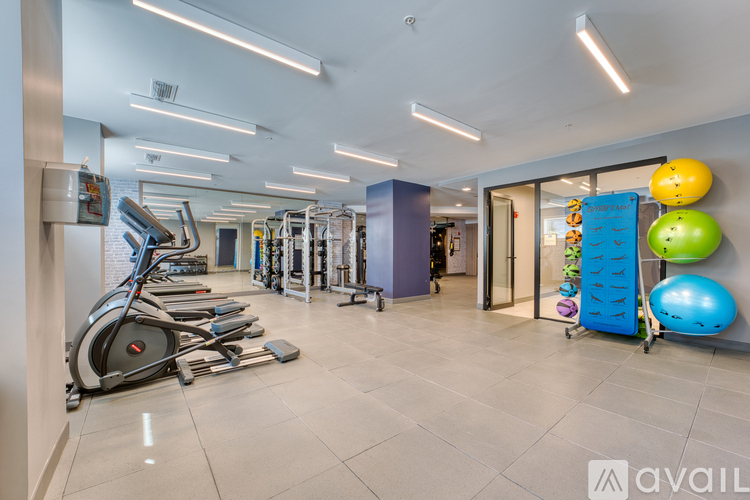 A gym with a variety of equipment including treadmills, weights, and exercise balls.