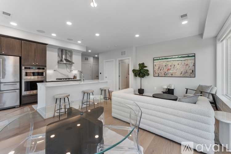 A modern kitchen with a glass table and a white sofa.