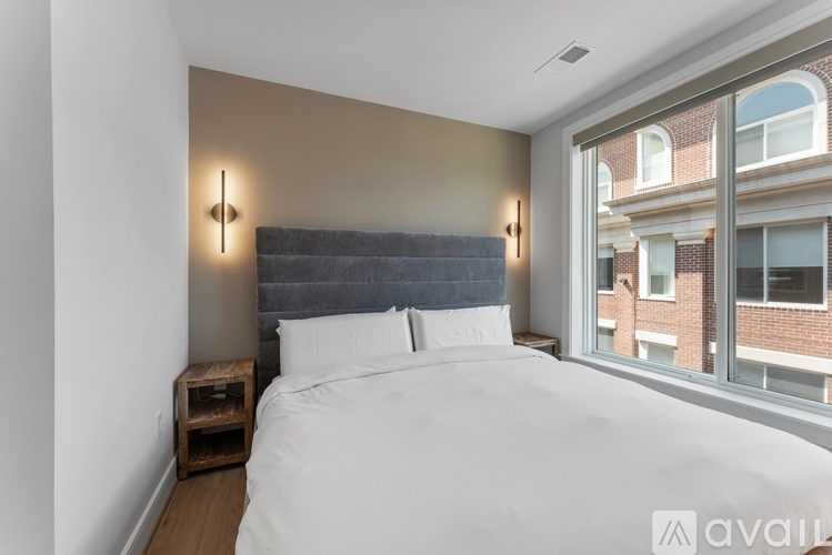 A bedroom with a large bed and a window overlooking a brick building.