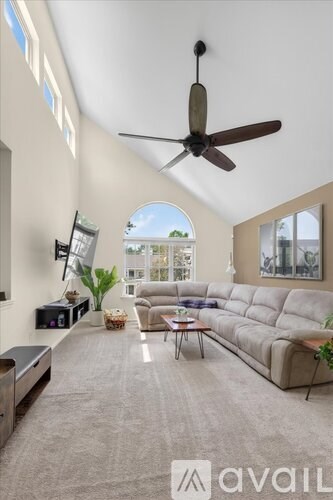 A living room with a large couch and a ceiling fan.
