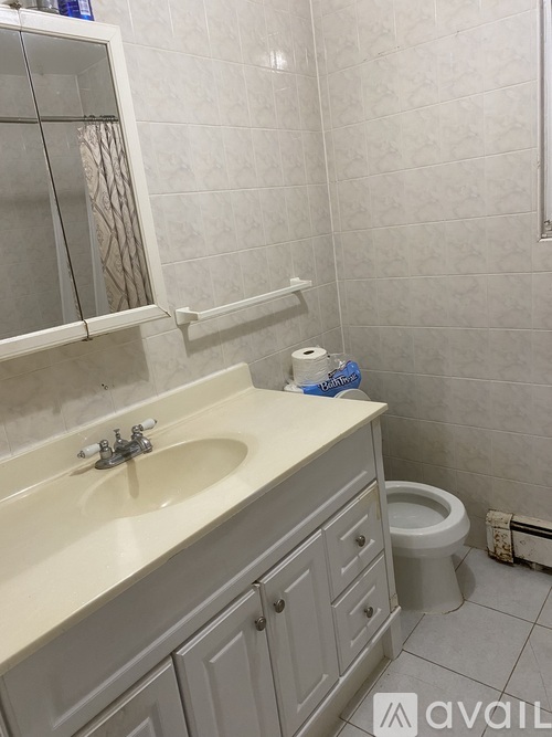 A bathroom with a toilet, sink, and mirror.