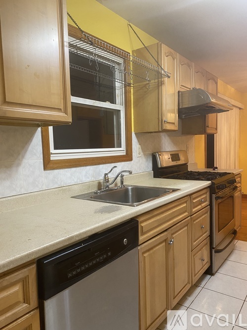 A kitchen with wooden cabinets and a black dishwasher.
