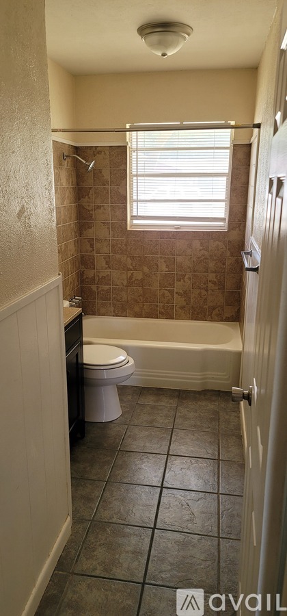 A bathroom with a toilet, tub, and window.
