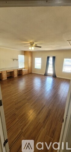 A spacious room with wooden flooring and a ceiling fan.