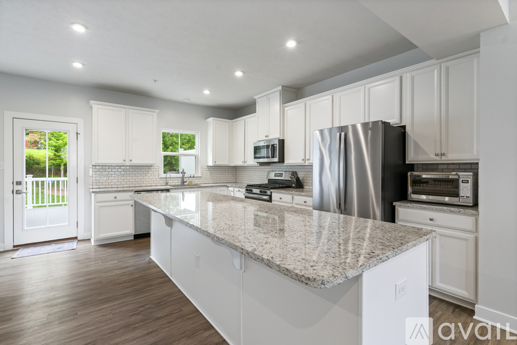 A kitchen with white cabinets and a marble countertop.