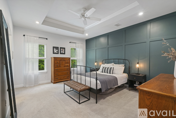 A bedroom with a bed, bench, and a ceiling fan.