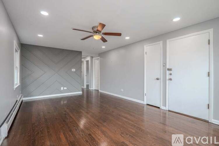 A spacious room with a ceiling fan and wooden flooring.