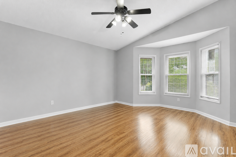 A room with a ceiling fan and wooden flooring.