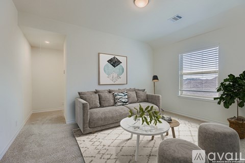 A living room with a grey couch, a white coffee table, and a painting on the wall.