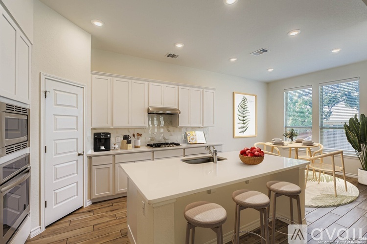 A kitchen with white cabinets and a large island with bar stools.