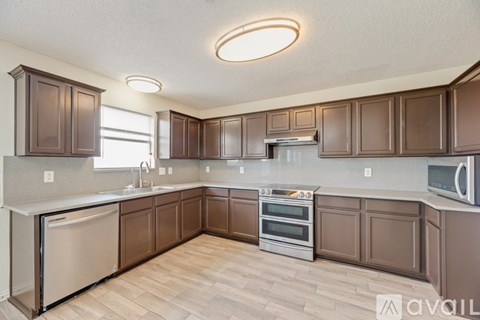 A kitchen with brown cabinets and a white dishwasher.