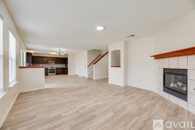 A spacious living room with a fireplace and a staircase.