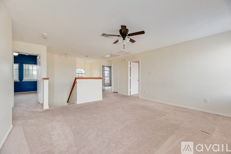 A spacious room with a ceiling fan and carpeted floor.