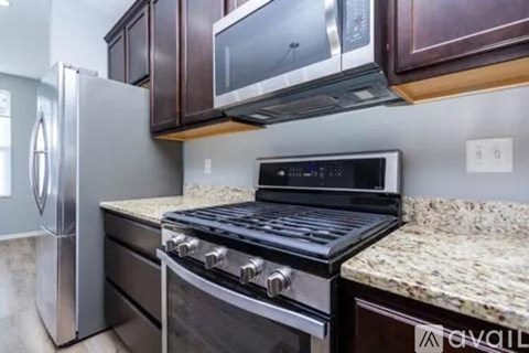 A kitchen with a black stove top oven and a silver refrigerator.