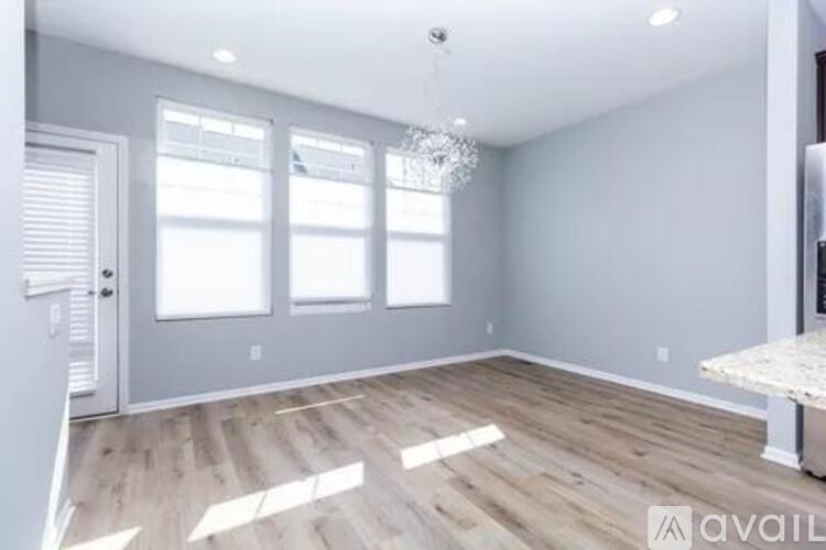 A spacious room with wooden flooring and a chandelier.