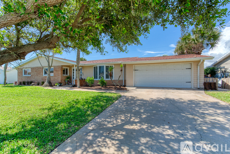 A house with a driveway and a tree in front.