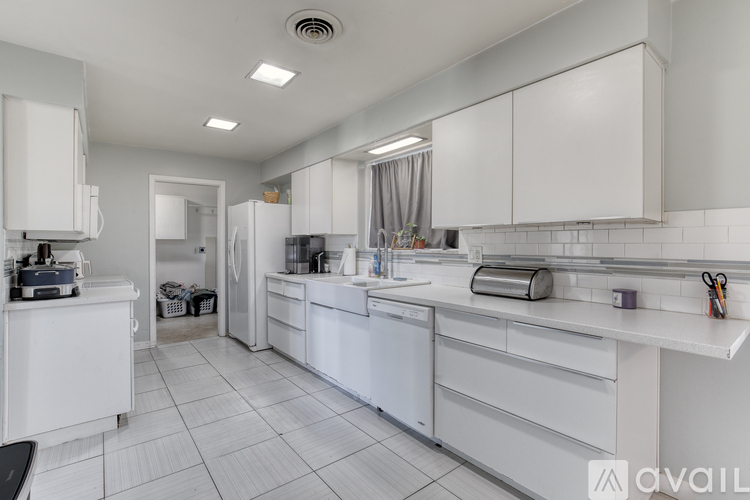 A white kitchen with a refrigerator, oven, and sink.