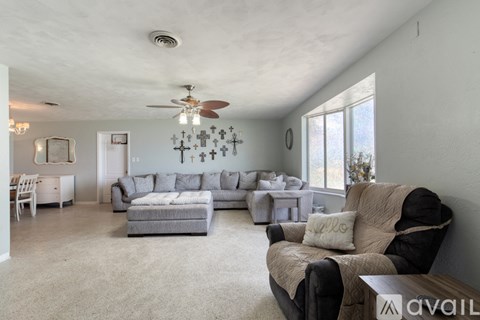 A living room with a grey couch and a fan on the ceiling.