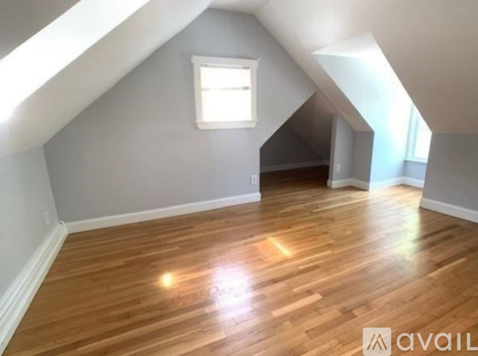 A room with wooden floors and a window in the attic.