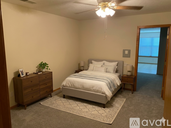 A bedroom with a bed, dresser, and ceiling fan.