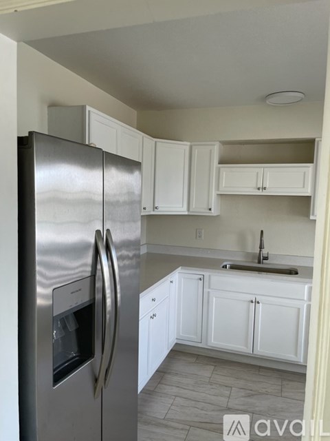 A kitchen with a stainless steel refrigerator and white cabinets.