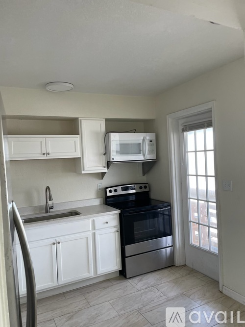 A kitchen with white cabinets and a black stove top oven.