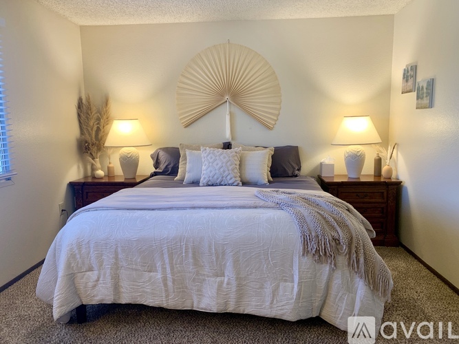 A bedroom with a large bed and a decorative fan on the wall.