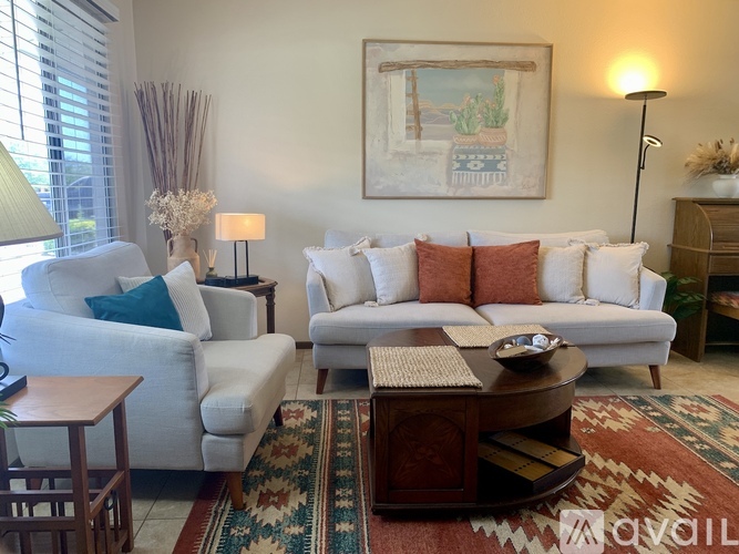 A living room with a white couch, a coffee table, and a painting on the wall.