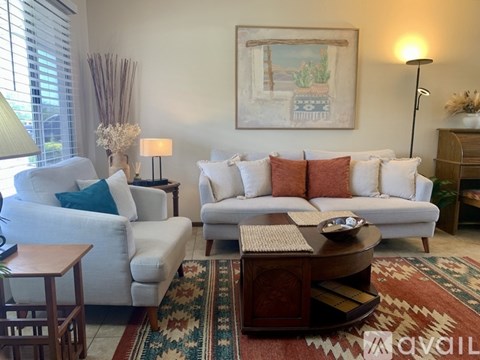 A living room with a white couch, a coffee table, and a painting on the wall.