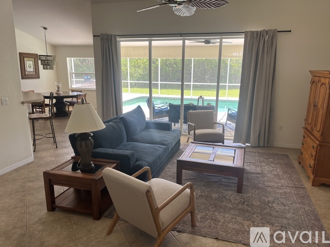 A living room with a blue couch, a wooden coffee table, and a large window with a view of a pool.
