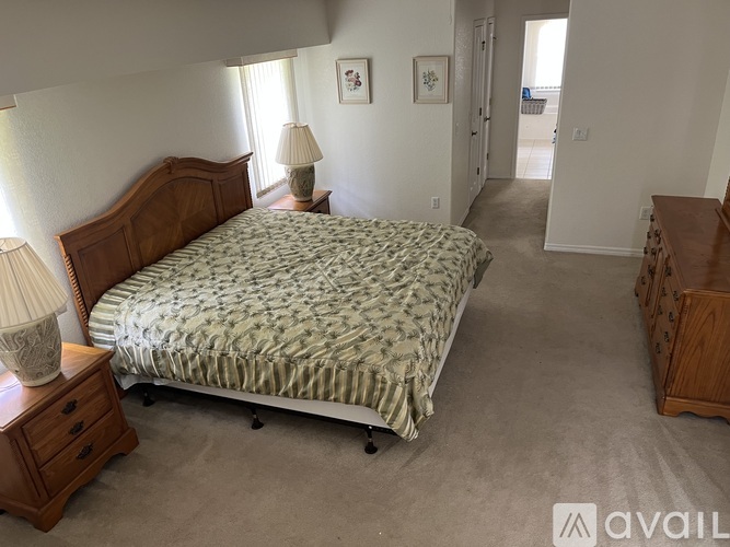 A bedroom with a large bed and a wooden dresser.