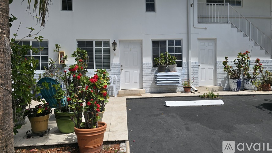 A white house with a black driveway and potted plants.
