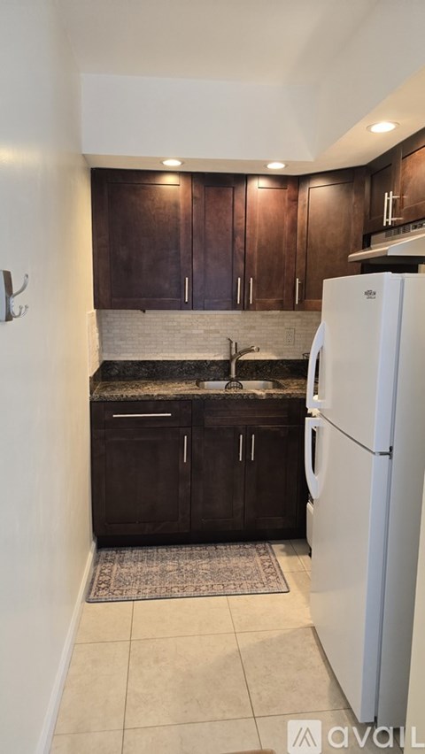 A kitchen with a white refrigerator and brown cabinets.