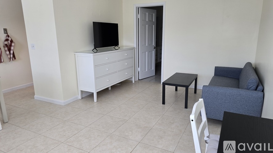 A living room with a white dresser and a black television.