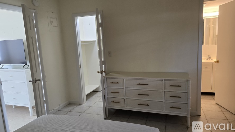 A white bedroom with a bed, dresser, and wardrobe.
