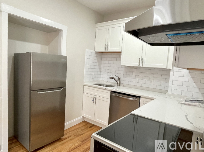 A kitchen with a stainless steel refrigerator and white cabinets.