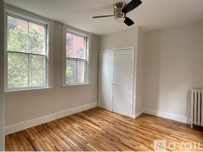 A room with a ceiling fan and two windows.