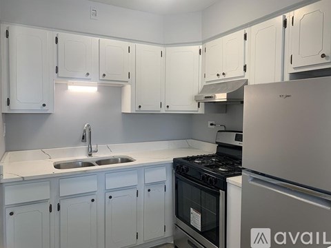 A kitchen with white cabinets and a stainless steel refrigerator.