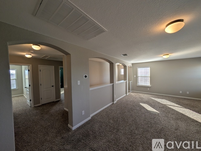 A spacious room with carpeted floor and a ceiling fan.