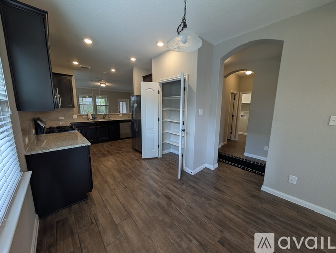 A kitchen with black cabinets and a wooden floor.