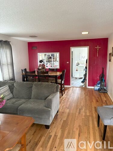 A living room with a grey couch and wooden floors.
